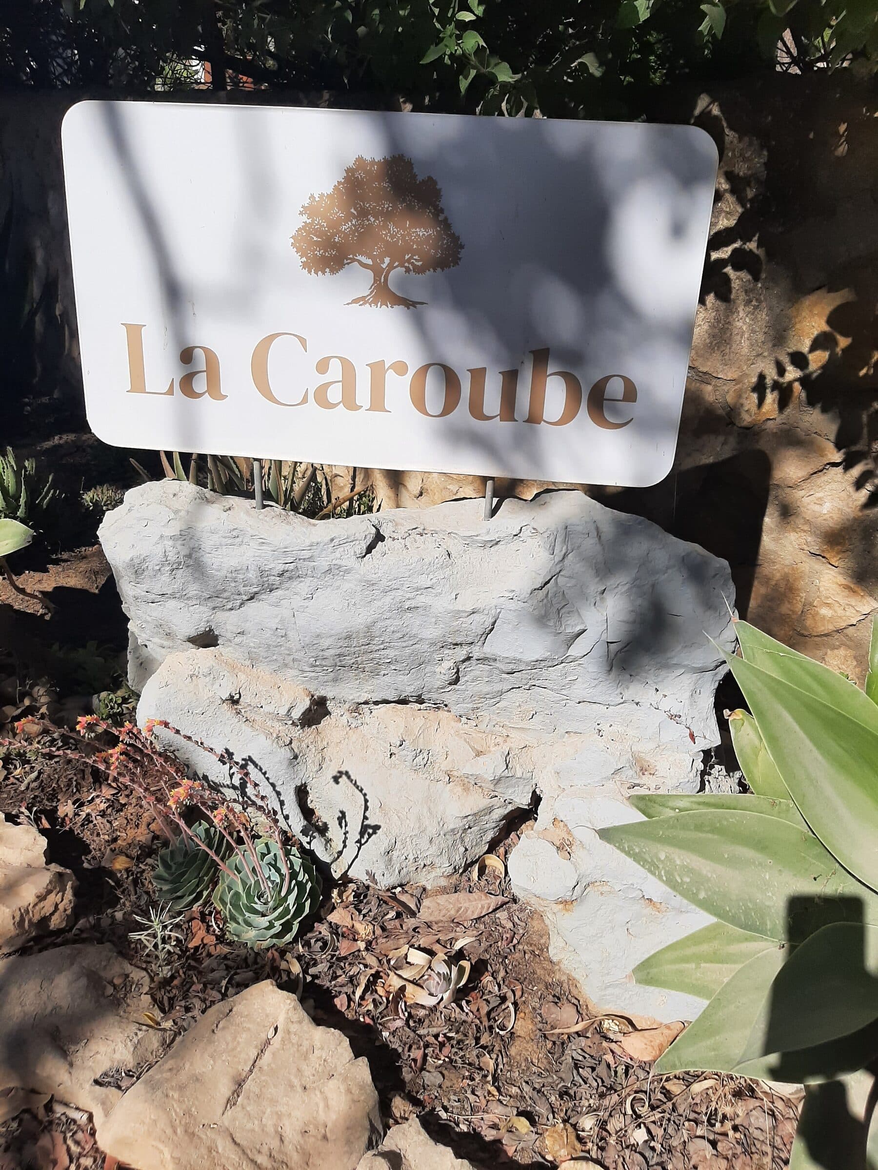 Le panneau La Caroube posé sur la roche, à l'entrée